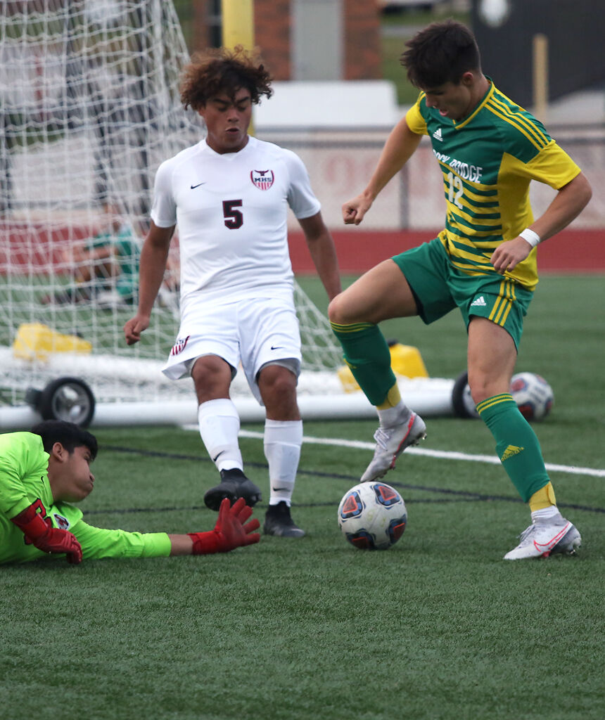 Marshall's senior goalkeeper Alex Vasquez reaches to get the ball from Rock Bridge senior Lucas Godon as senior Chris Hernandez defends it, in the second half of their game